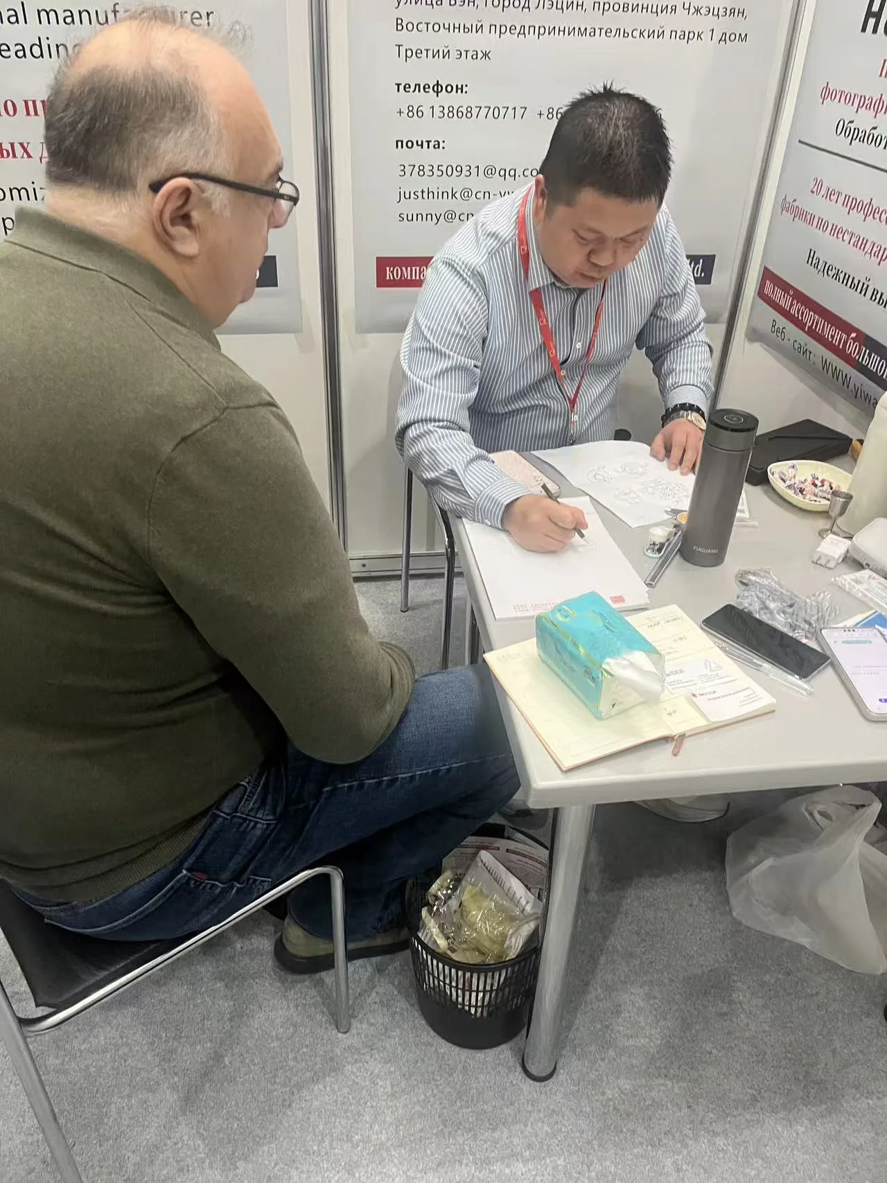 YIWAN representative reviewing a drawing with a visitor at Moscow Fastener Expo